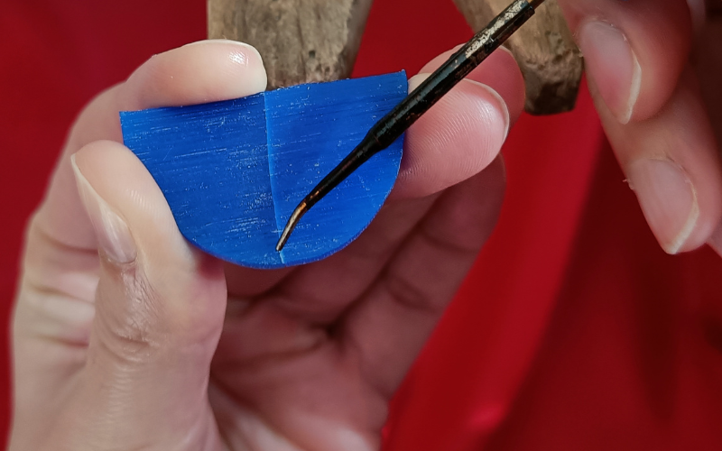 Close up of hands holding a piece of blue wax point of wax heating pen is on the join