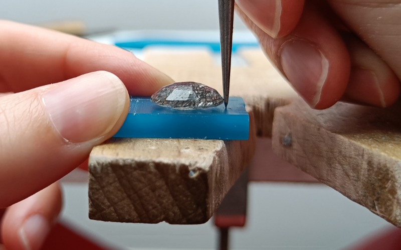 Piece of wax with a stone on top, a scribe is next to the stone point on the wax