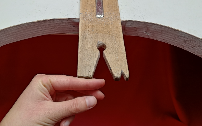 Bench peg with forefinger of left hand braced against it 