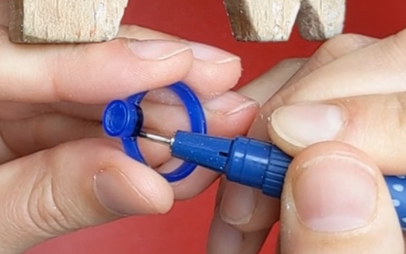 sHand holding a solitaire ring and the other hand is coloring the side of the solitaire with marker 