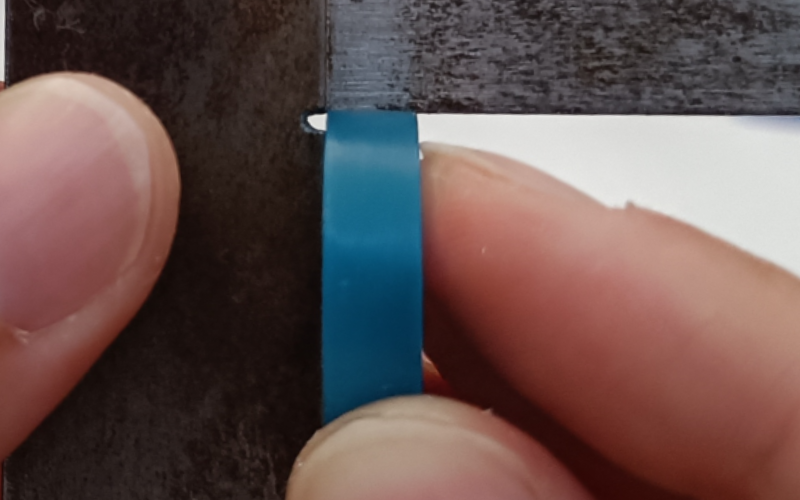 Close up of hands holding a set square and measuring a turquoise ring. No gaps visible
