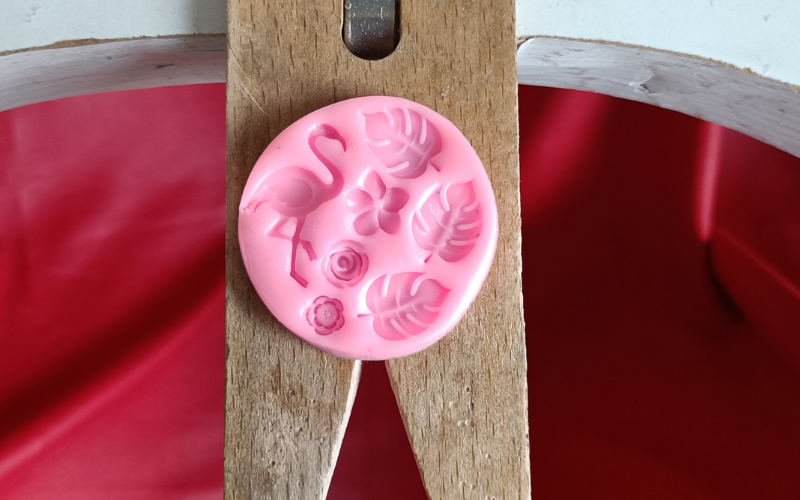 close up of polymer clay mould with different lead and flower imprints and one bigger flamingo