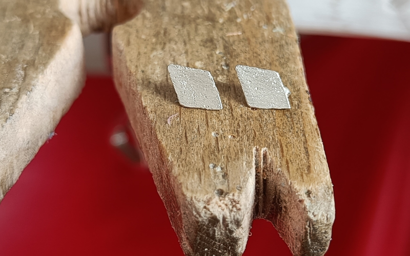 close up of bench peg with 2 silver diamond shaped pieces. Both have porosity on the surface