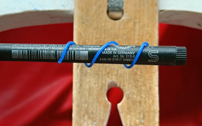 Close up of piece of blue wax wire wrapped around a pen 
