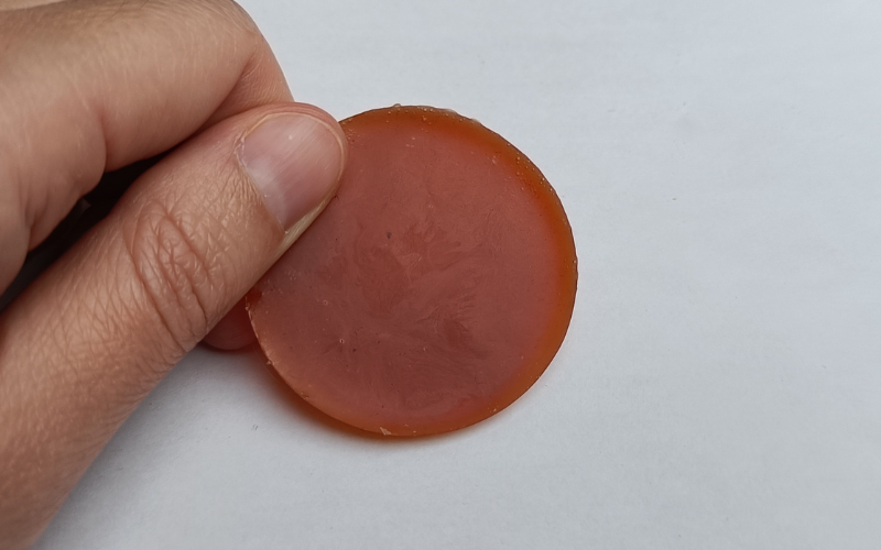 Round piece of newly melted orange wax. 