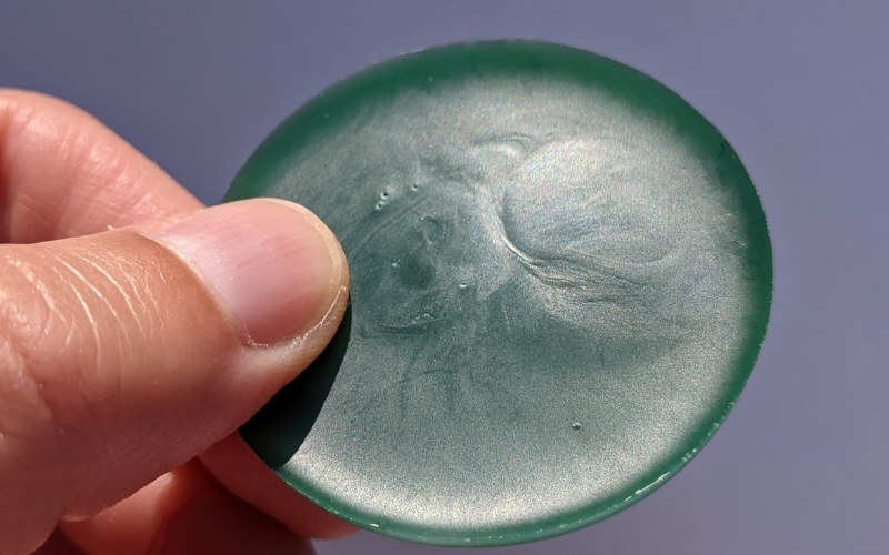 Round piece of newly melted green wax