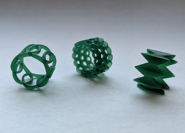 3 wide rings from green wax. Left a repeating pattern ringwith big overlapping circles, middle a ring with 3 rows of holes, right a ring with elongated diamond shapes as repeating pattern