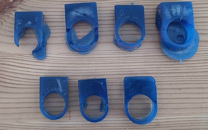 close up of 7 blue wax rings. Top row of 4 rings are terrible parts of the ring are missing and loads of air bubbles. Bottom row 3 ar better looking