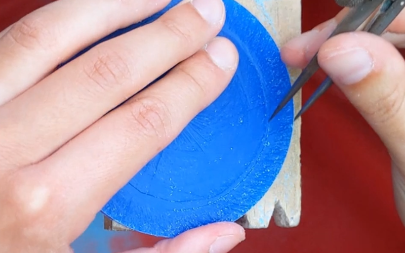 Close up of hands marking the size on a piece of blue bangle wax 