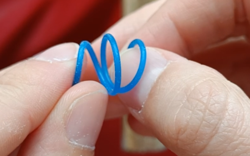 Close up of piece of blue wax wire removed from the pen , wire is looped 