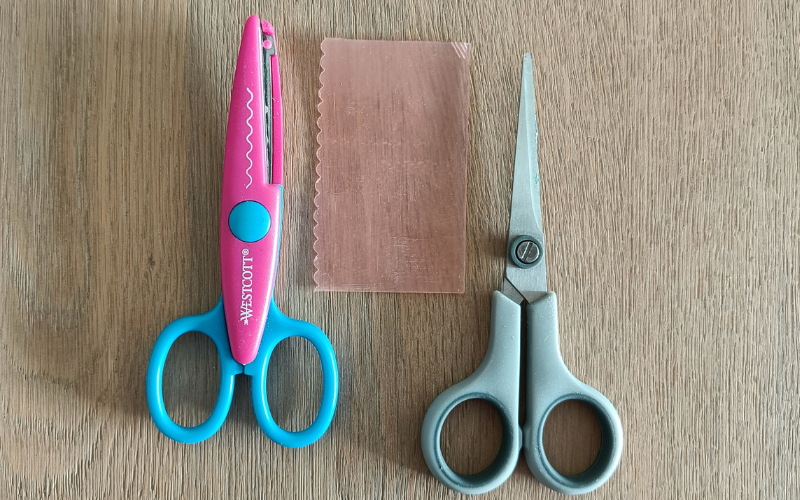 pink sheet wax with regular scissors and scalloped edge scissors next to it. 