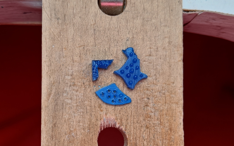 Close up of scrap pieces of blue wax on a bench peg. The pieces have been used to practice different techniques of a wax pen: granulation, melting holes and a groove texture.