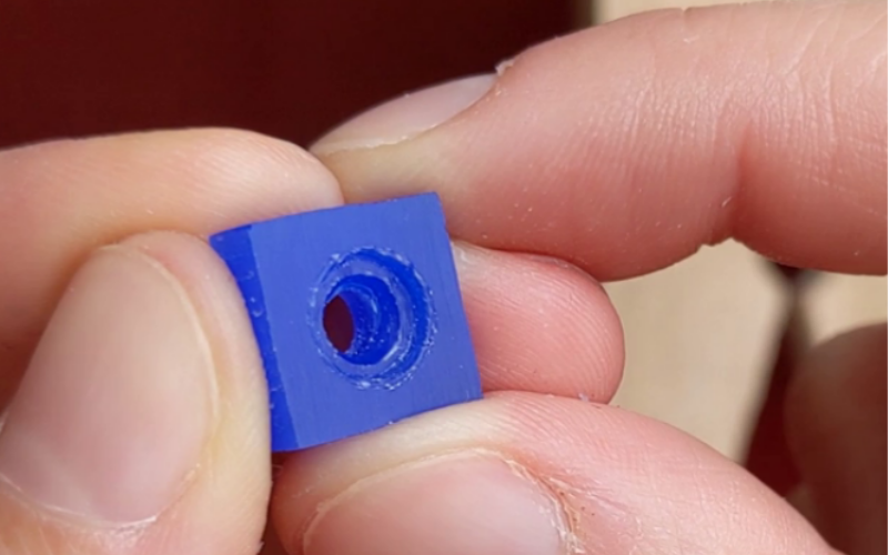 Hands holding a small piece of blue wax with a round hole inside. You can see the seat of the setting