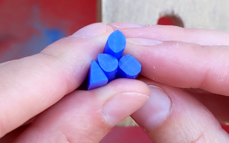 close up of hand holding 4 pieces of blue wax. The pieces are pear, marquise, triangle and octagon shaped.