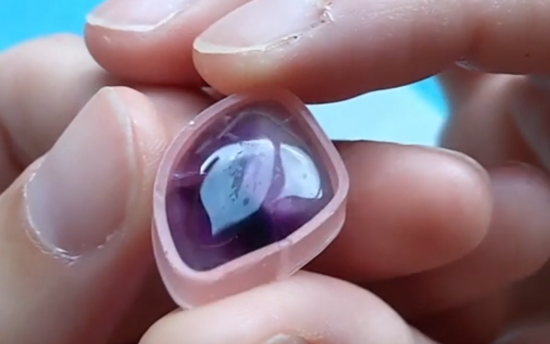 Close up of hands holding a bezel made from pink sheet wax for a big rectangular amethyst