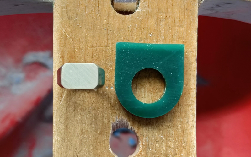 Close up of bench peg with a octagon signet ring in silver next to a piece of green signet shaped ring tube