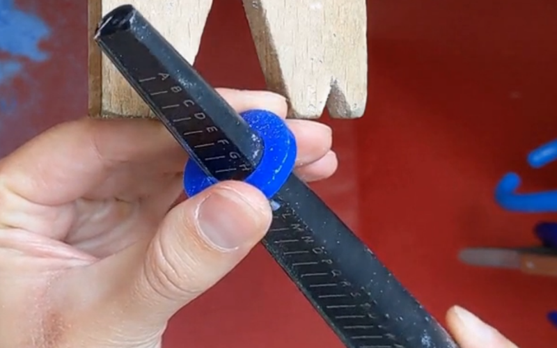 Hands on a bench peg sizing the ring with a wax ring sizer