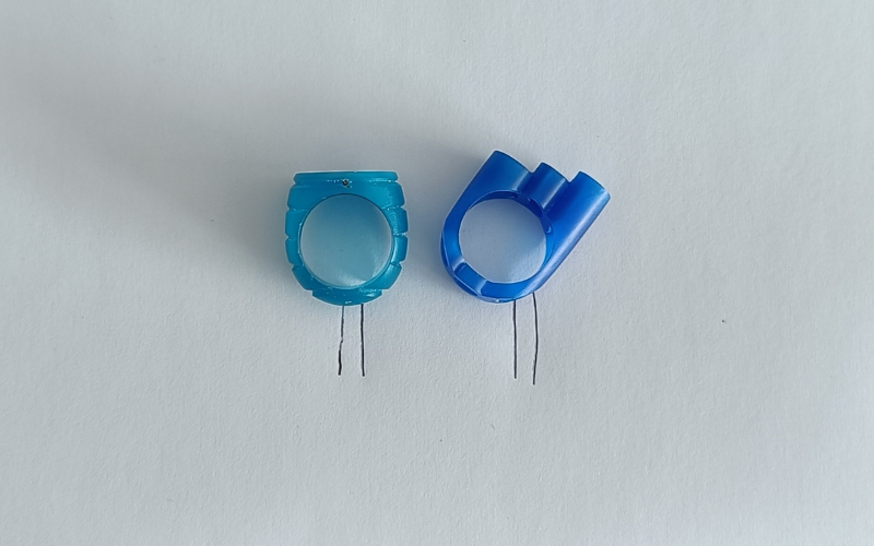 Paper with a turquoise wax ring and a blue wax ring lying on top, underneath the rings a rectangle is drawn to indicate where the sprue should be