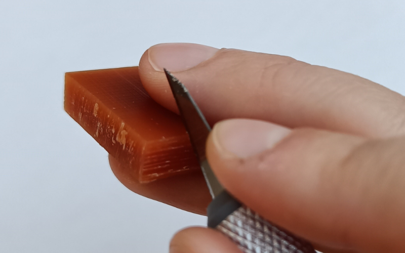 Orange piece of wax with stanley knife in it