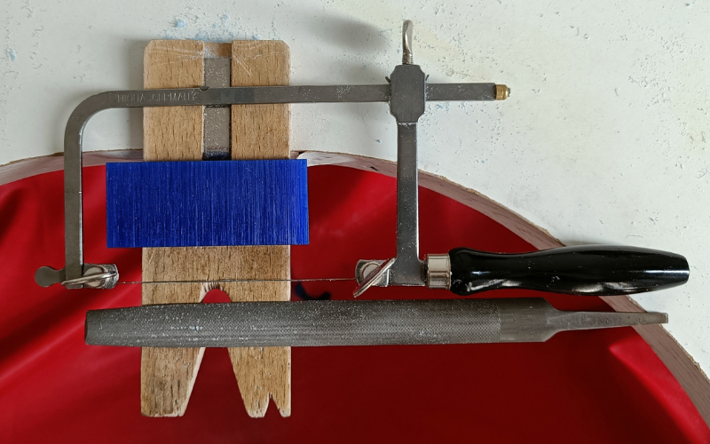 Close up of bench peg with a saw, file and slice of blue wax