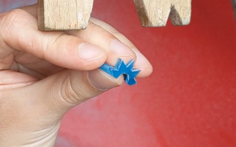 Close up of hands holding a turquoise wax ring. Part of the ring sticks out, the middle finger is supporting the part that sticks out from underneath providing ectra support. 