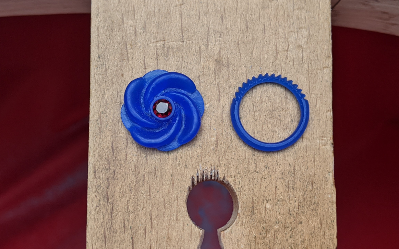 A swirl shaped pendant with a round garnet in the centre and a court shape ring with a pattern filed into half the band