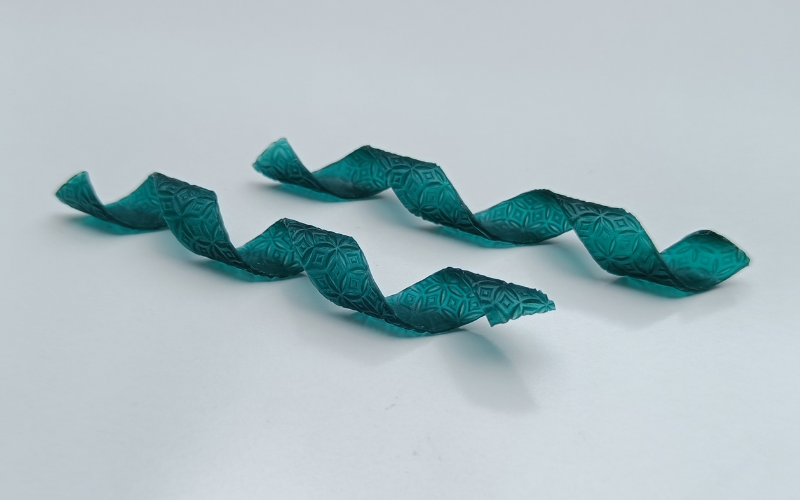 A pair of swirly earrings from green wax. The wax is textured