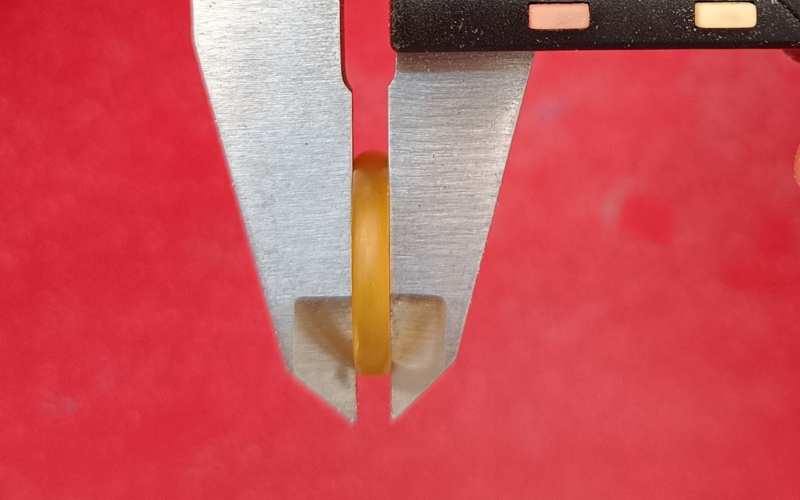 Close up of a court shaped wax ring in the jaws of the calipers. You can see the curve of the court shape is not symmetrical