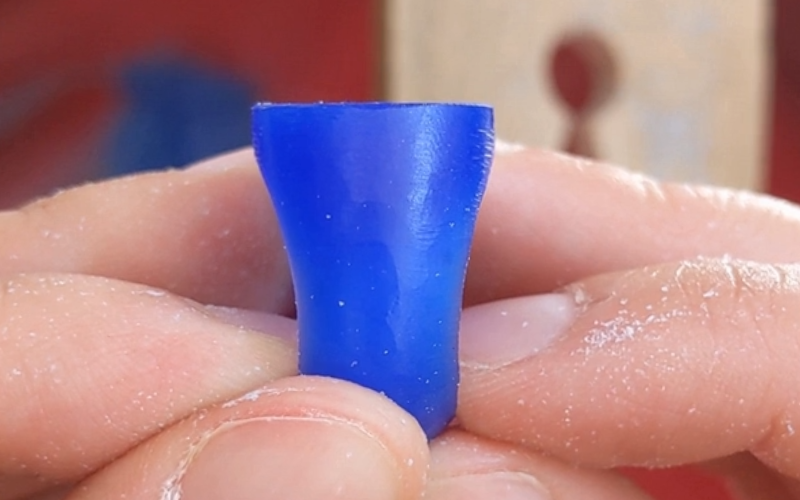 Close up of hands holding a blue wax ring that is still in process. Looking at the ring you can see that the left and the right side are not similar