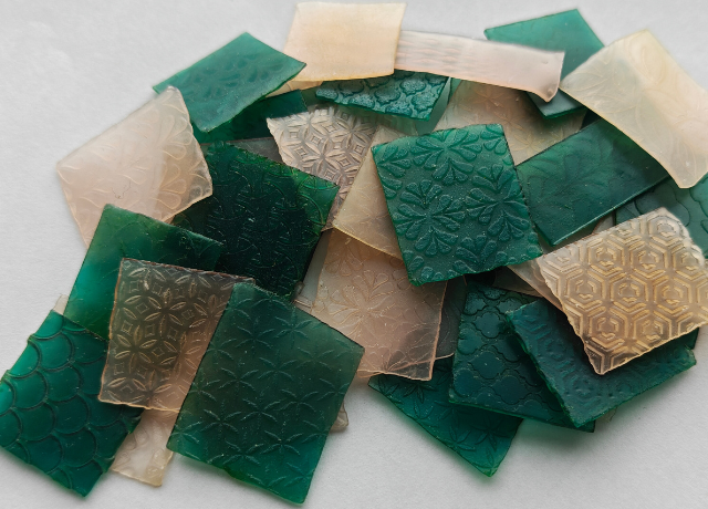 Big pile of small green and pink sheet wax squares that are all textured differently
