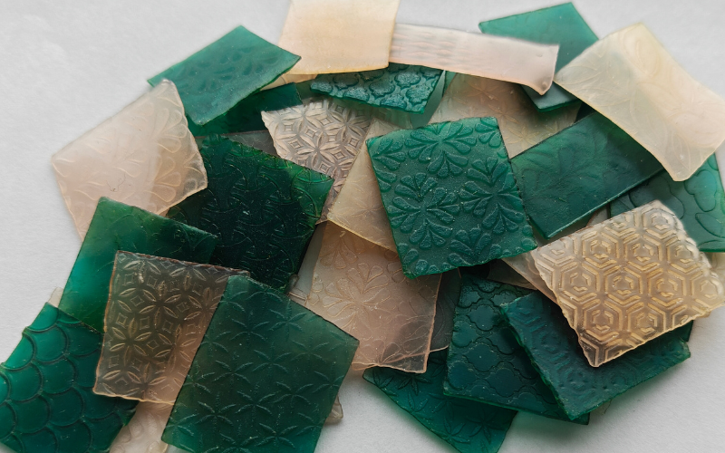 Big pile of small green and pink sheet wax squares that are all textured differently