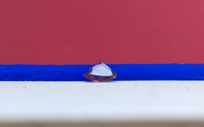 Slice of wax on a bench with a round stone upside down in front of it. The culet fo the stone goes over the wax