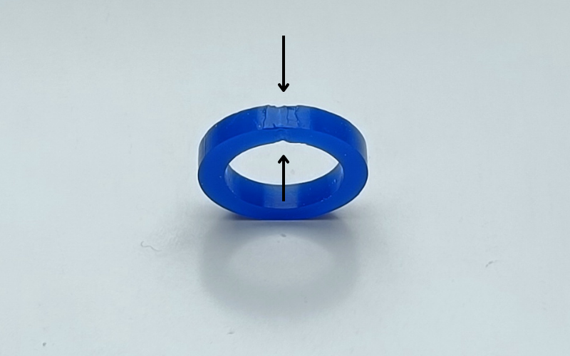 Close up of a blue wax ring that's been melted together. 2 Arrows point to the parts where you can see the joint has become thinner than the surrounding.
