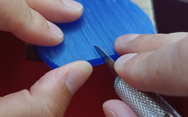 Piece of wax on a bench peg with a stanley knife inside it. The stanley knife is tilted up 