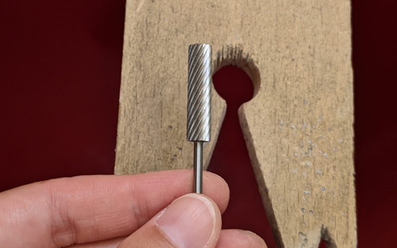 Close up of a hand holding a cylinder wax burr