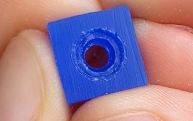 Close up of hands holding a piece of blue wax with a hole inside. the seat inside the hole is very wide